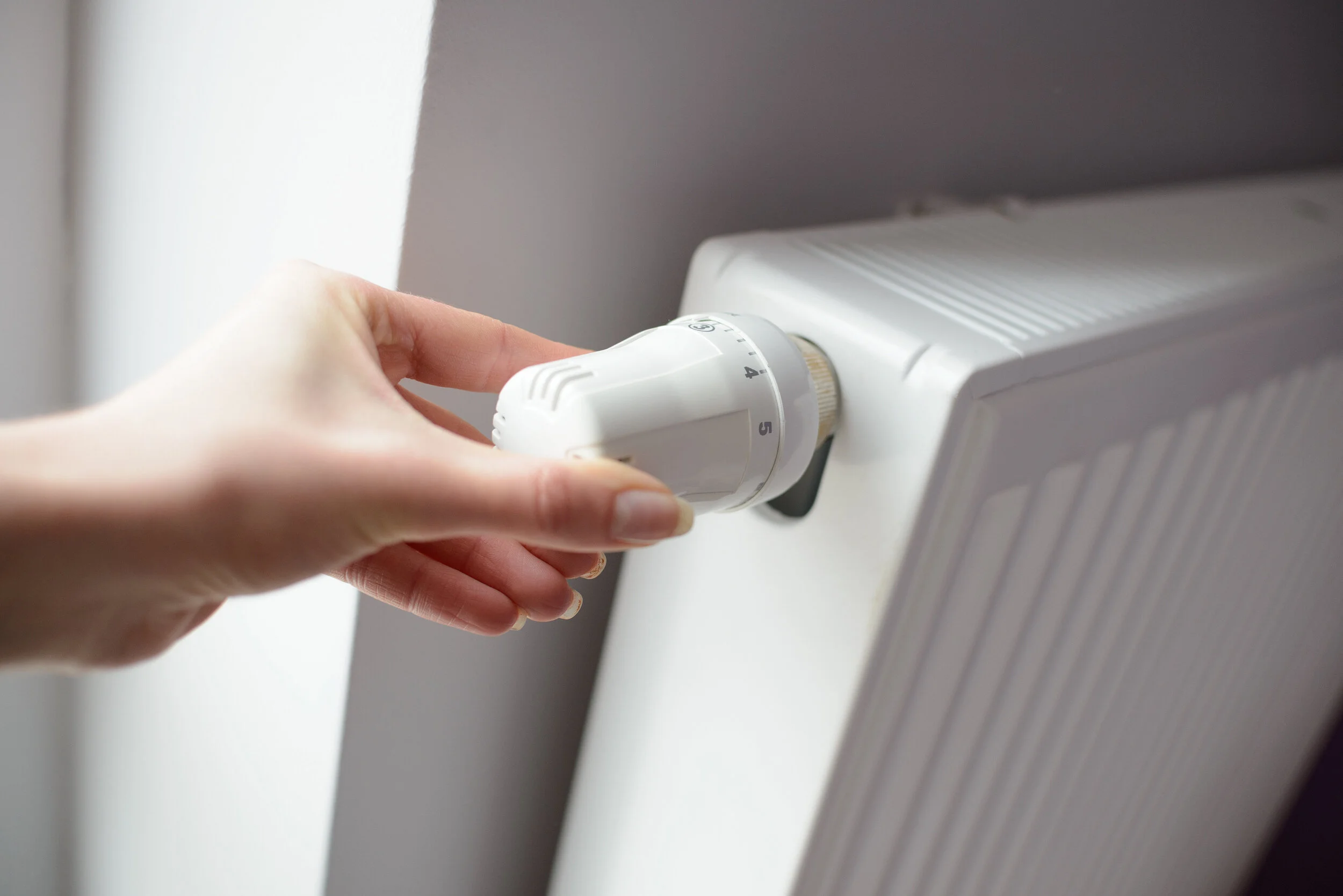 Hand adjusting a radiator thermostatic valve
