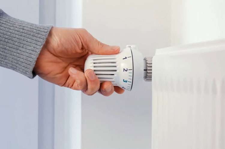 Hand adjusting a radiator thermostatic valve